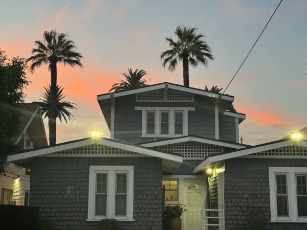 A tropical-style house featuring palm trees during sunset.